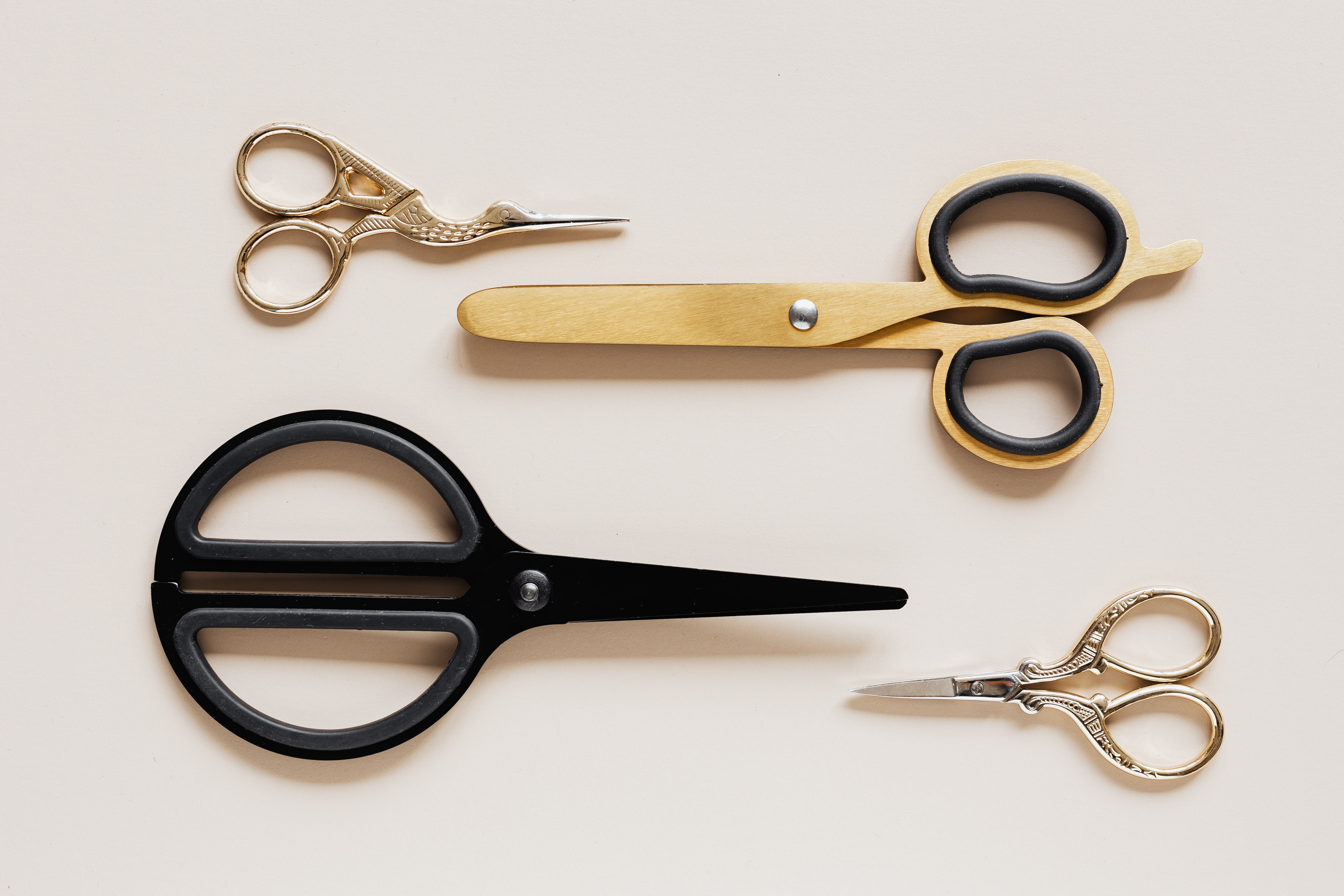 four pares of scissors, of different styles, two metal, one wood, and one black plastic. Two point right and two point left.