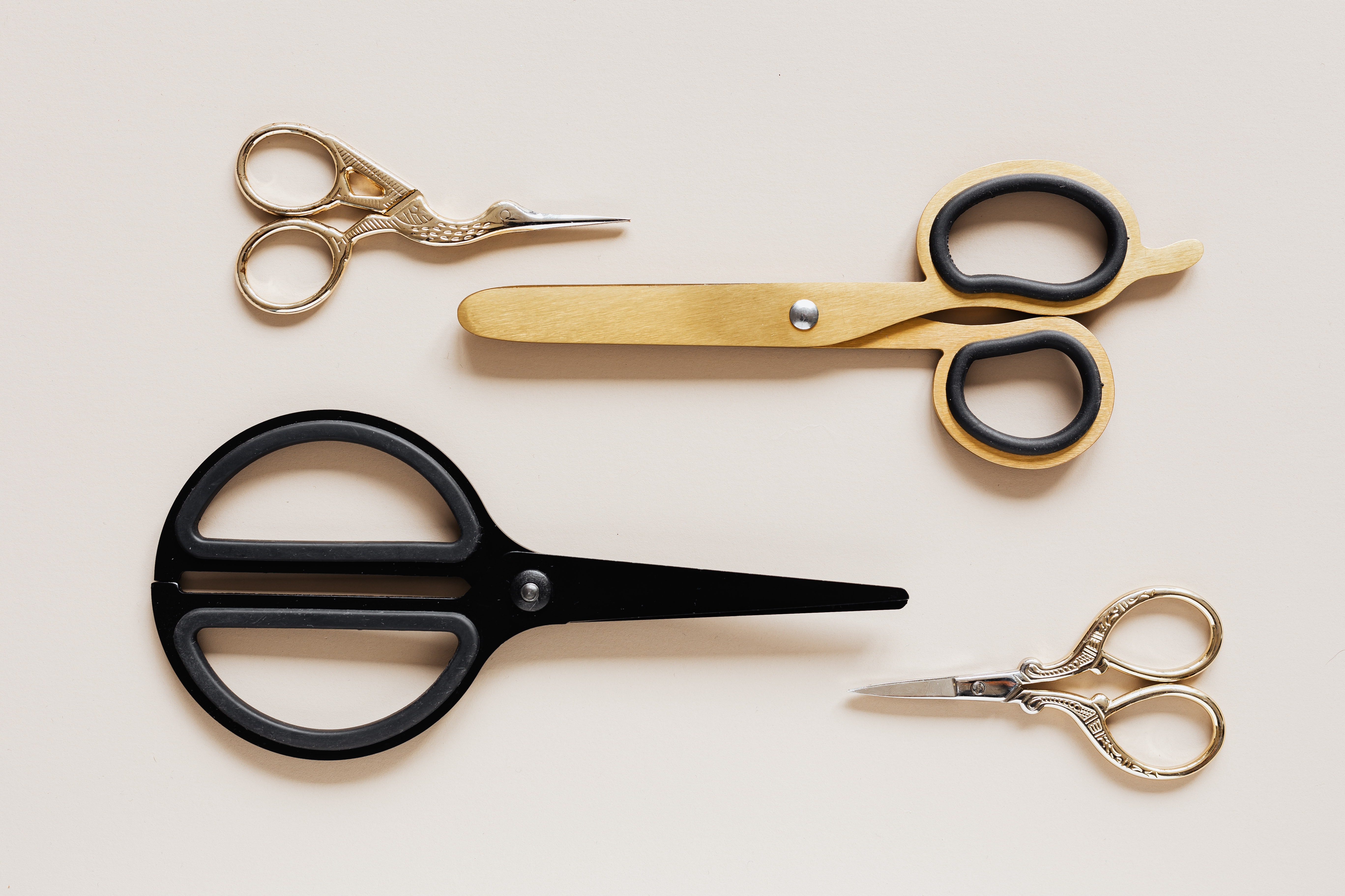 four pairs of scissors, of different styles, two metal, one wood, and one black plastic. Two point right and two point left.